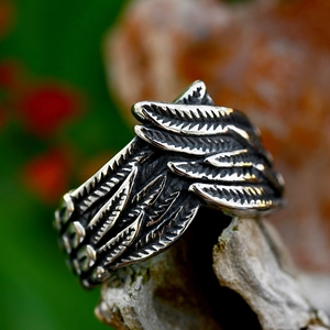 Retro-Ring aus Edelstahl mit Engelsflügeln auf einem natürlichen Holzsockel