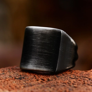 Men's square signet ring in black brushed stainless steel on industrial stone