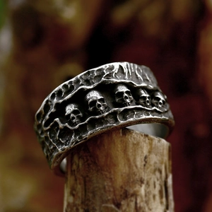 Gothic skull carved stainless steel ring with vintage oxidation finish on wood base