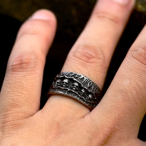 Macro detail of gothic stainless steel ring with five small skulls and lava texture
