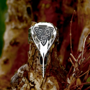 Vintage stainless steel crow skull ring with black Celtic knot engraving on a wooden branch