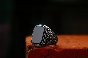 Gedetailleerde macro-opname van een retro rvs ring met zwarte onyx steen op een baksteen