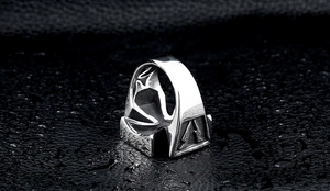 Macro shot of men's stainless steel ring with pine tree relief on a dark water-drop surface