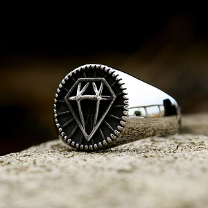 Vintage stainless steel signet ring with diamond pattern on a textured stone surface