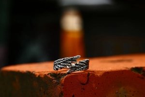 Macro detail of retro stainless steel feather ring with oxidized finish on red brick