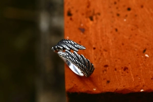 Detailed macro view of retro feather wing stainless steel open ring with silver finish