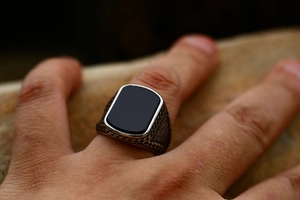 Detail van een vintage roestvrijstalen ring met zwarte agaat op een natuurlijk rotsoppervlak