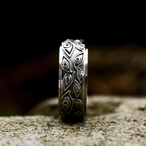 Vintage stainless steel spinner ring with gothic evil eye relief on a stone surface
