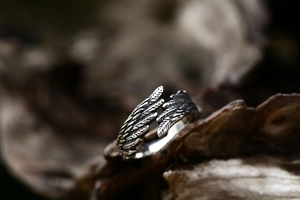 Detailed macro view of vintage stainless steel angel wing ring with carved feather texture