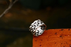Detailed close-up of a stainless steel Celtic knot ring on a rustic red brick surface