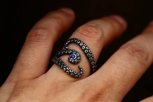 Macro shot of octopus tentacle ring in vintage steel with a blue gemstone inlay