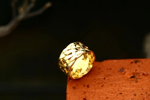 Macro shot of gold wide-band ring with intricate woven Celtic knot texture on metal