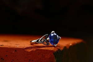 Detail of Celtic knot silver ring with a square blue sapphire-like gemstone in a four-prong setting