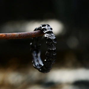 Close-up of vintage skull band ring in black stainless steel on rusted wire background