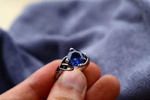 Detail view of a vintage stainless steel ring with a large blue zircon and Celtic knot band