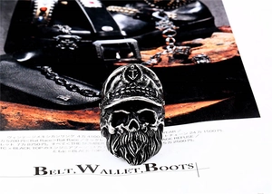 Close-up of vintage steel skull ring with anchor hat on a dark leather magazine background