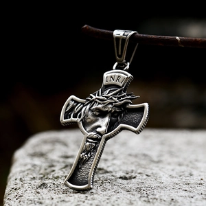 Vintage stainless steel Jesus cross pendant with INRI engraving on a rustic stone background