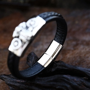 Detailed view of men's woven leather bracelet with silver motorcycle metal charm decoration