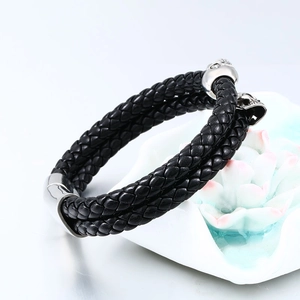 Primer plano de pulsera trenzada de cuero negro con dije de calavera plateada de metal