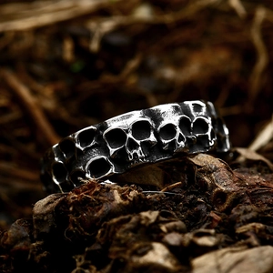 Macro shot of punk style stainless steel skull ring on natural wood and leaves background