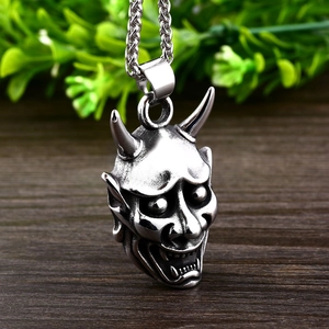 Pendentif masque Hannya japonais en acier inoxydable sur fond en bois rustique