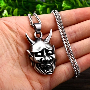 Gros plan détaillé du pendentif masque Hannya en acier inoxydable avec chaîne de blé fine