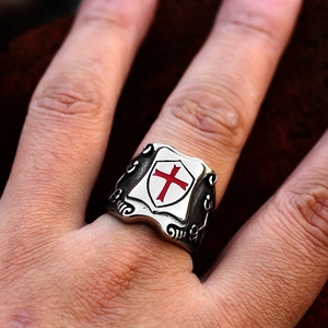 Detailed close-up of a vintage steel ring with a red cross shield and scrollwork detail