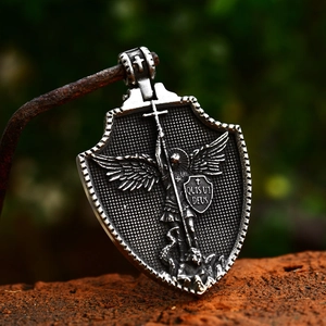 Vintage stainless steel St. Michael shield pendant with antique finish on a rustic hook