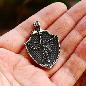 Macro detail of Archangel Saint Michael shield pendant in hand for scale and size