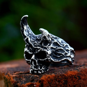 Vintage punk skull ring with horn details and lava texture on a rustic stone background