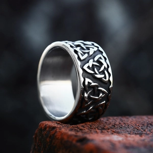 Macro detail of vintage Celtic Triquetra knot relief pattern on a wide stainless steel ring