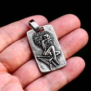 Close-up of vintage stainless steel rectangular pendant featuring a skeleton relief design