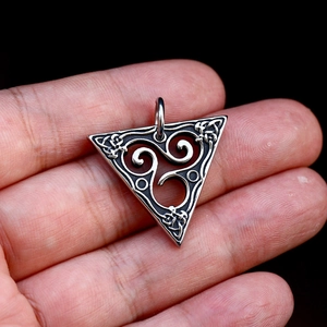 Détail d'un pendentif triangulaire en acier vintage avec gravure du nœud triskèle celtique