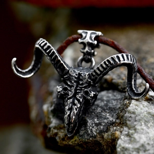 Macro shot of vintage stainless steel ram skull pendant on natural rock with leather cord