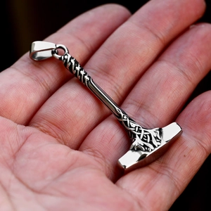 Macro shot of stainless steel Mjölnir pendant with Celtic knots in hand for scale