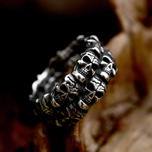 Primer plano de anillo de acero inoxidable con calaveras múltiples y acabado plata vieja