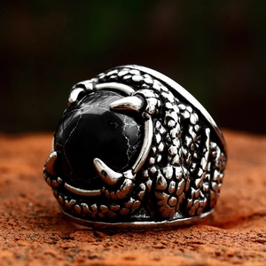 Vintage stainless steel dragon claw ring with black turquoise stone inlay on brick background