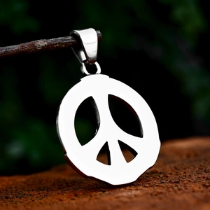 Polished stainless steel peace sign pendant hanging on a natural wooden branch