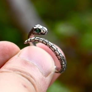 Retro stainless steel snake ring with green stone eyes on a person's finger