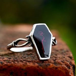 Gothic vintage stainless steel coffin ring with red rose on rustic brick background