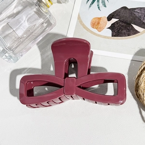 Detail of a large dark pink bow-shaped hair claw clip made of durable soft resin material