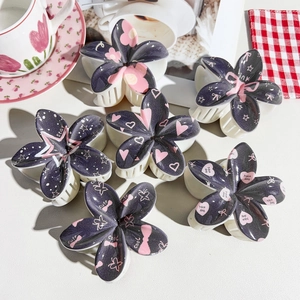 Detailed view of six floral hair claws with cute heart and star prints on matte finish