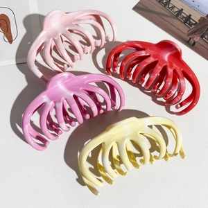 Detail of four large marble pattern silicone hair claws in pink, red and beige colors