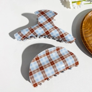 Detailed view of blue and brown plaid hair claw clips on white textured background