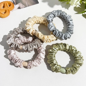 Close-up of five satin scrunchies in Morandi colors with glossy resin cylindrical buckles