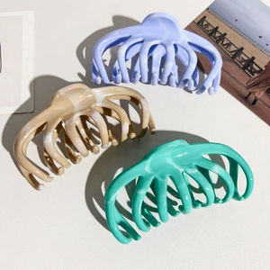 Detailed view of large octopus-shaped hair claws in lilac, marble brown and emerald green