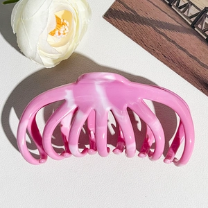 Macro view of large pink marble resin hair claw clip with elegant ink texture design