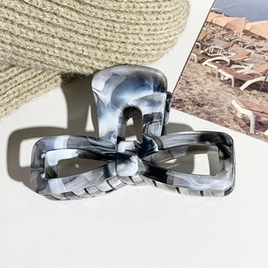 Detail of elegant marble texture hair claw clip with bow shape on aesthetic background
