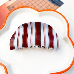 Détail d'une pince à cheveux demi-cercle à rayures rouges et blanches sur un plat décoratif