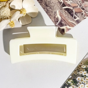 Detail view of cream matte square claw clip on a textured background with dried flowers